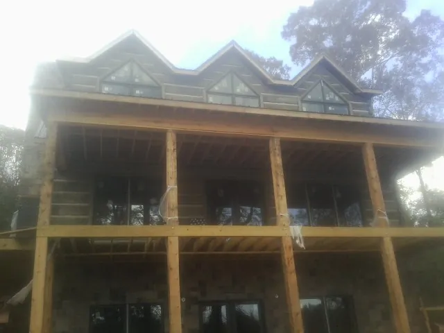 Dormers and porch framing on a large log home under construction — Roof Coating work by our crew in Minnetonka