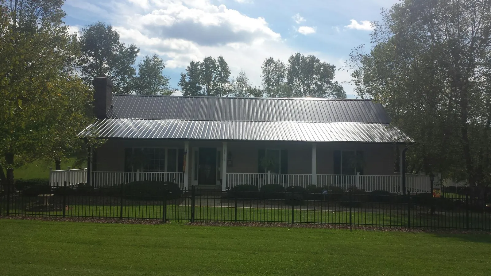 Gray metal roof on a brick ranch with a full width front porch — Gutter Guard Installation work by our crew in Minnetonka