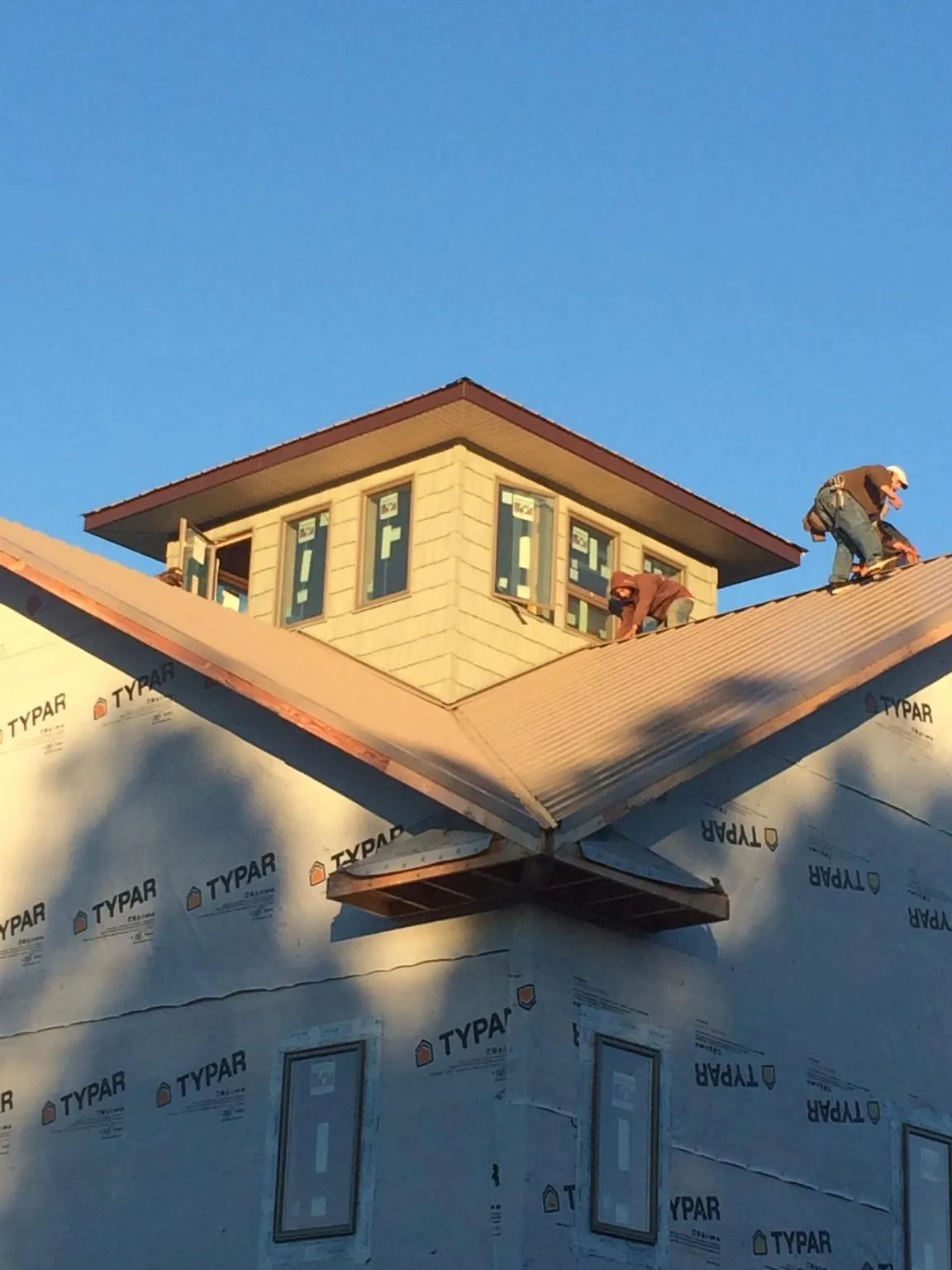 Roofers working around a rooftop cupola on a new metal roof at sunset — Roof Waterproofing in Minnetonka by Roofing Brothers
